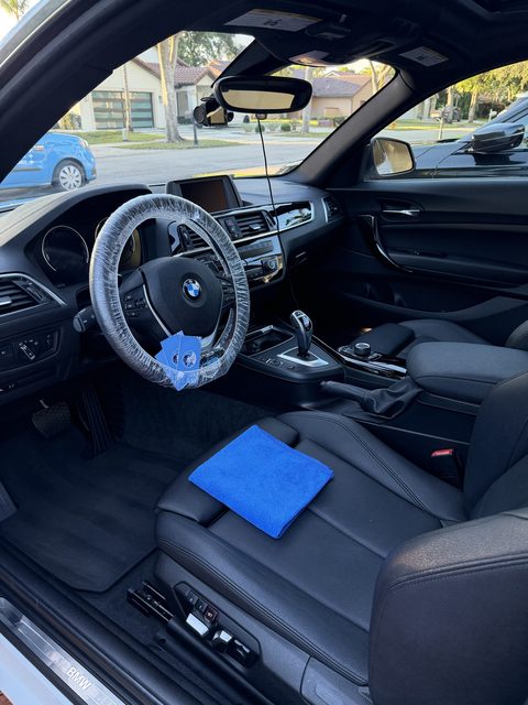 BMW 2 Series black leather interior after detailing, steering wheel covered during service