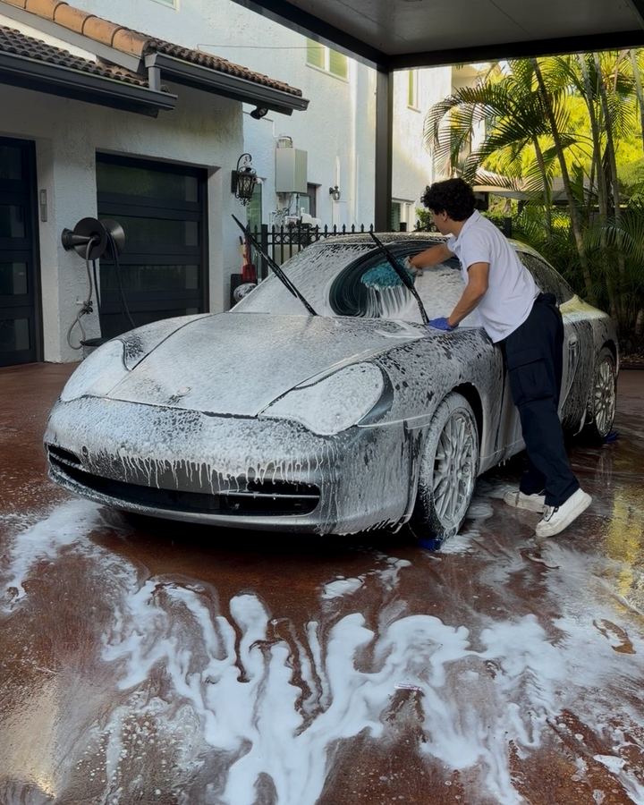Andres foam-washing a silver Porsche 911
