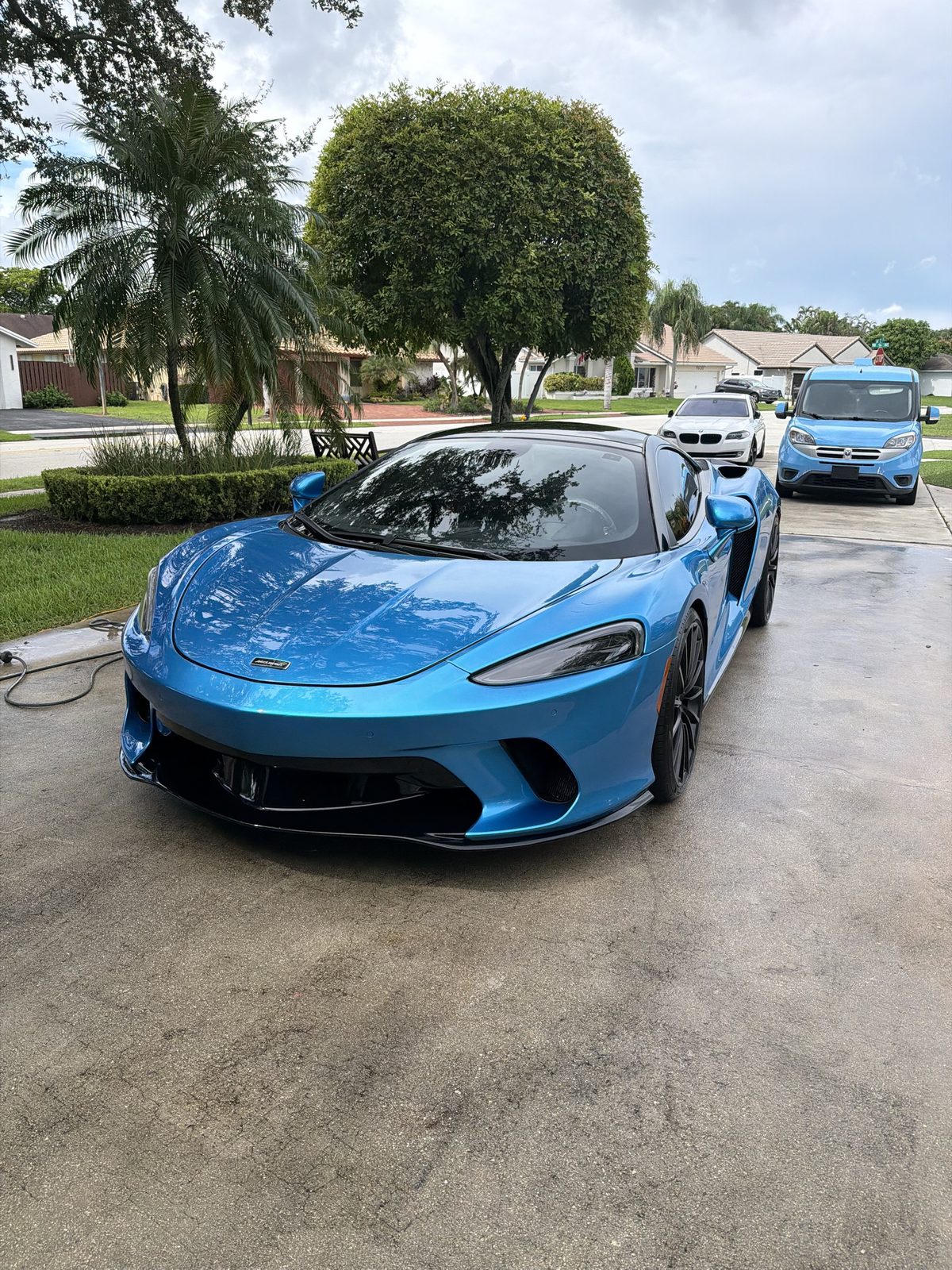 Blue McLaren GT with a glossy finish in a Broward driveway
